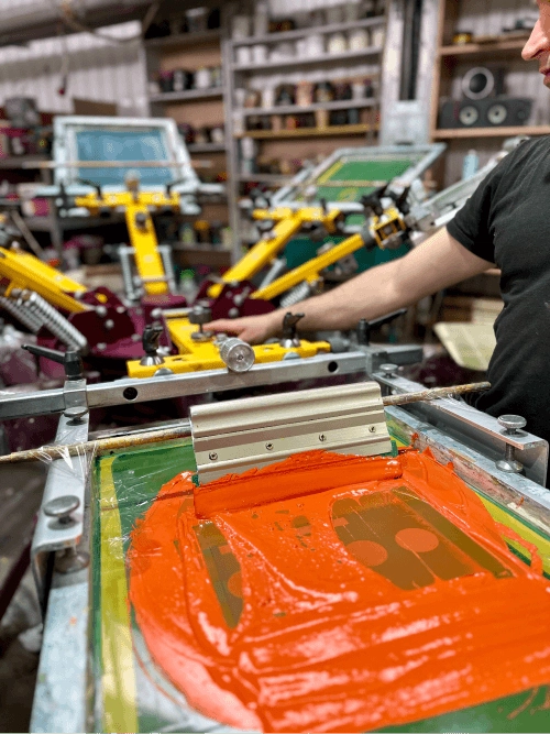 Step-by-step process of applying ink through a screen onto a t-shirt using a screen print machine